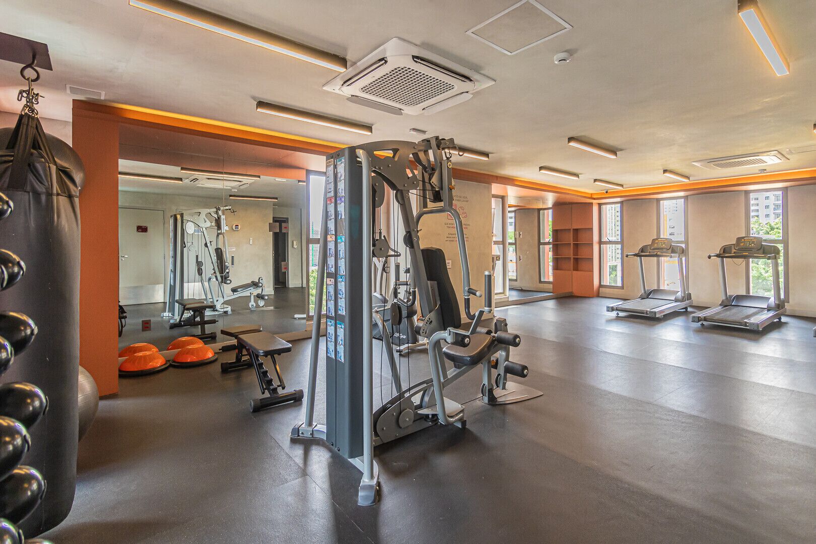A gym with various exercise equipment, including a squat rack, treadmills, and weight machines.