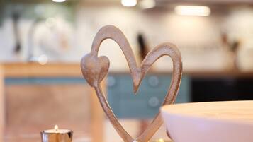 A metal heart-shaped decoration on a wooden surface with a lit candle nearby.