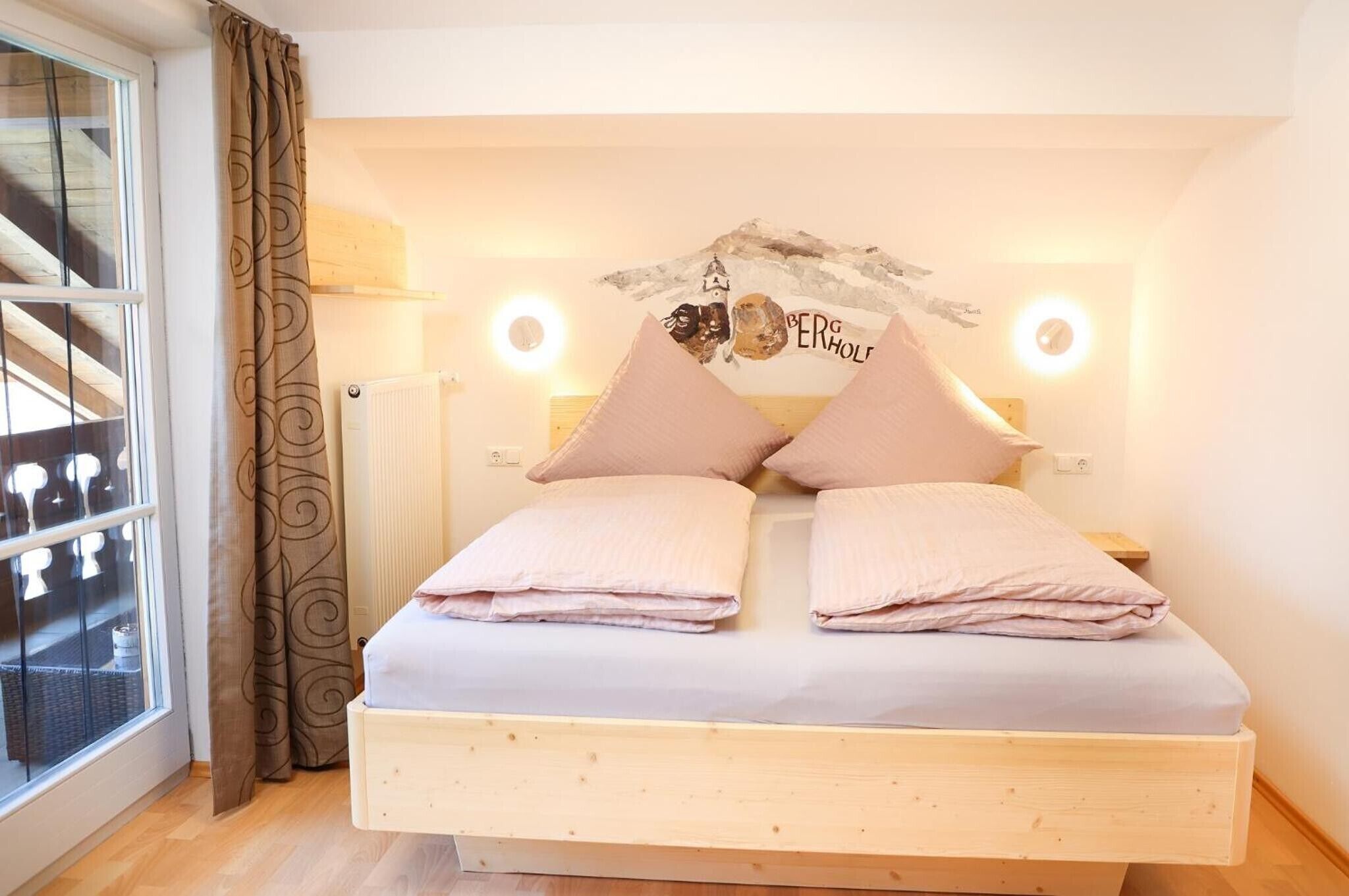 Ein Schlafzimmer mit Bett, Vorhängen, einer Wand mit einem Logo und einem Fenster.