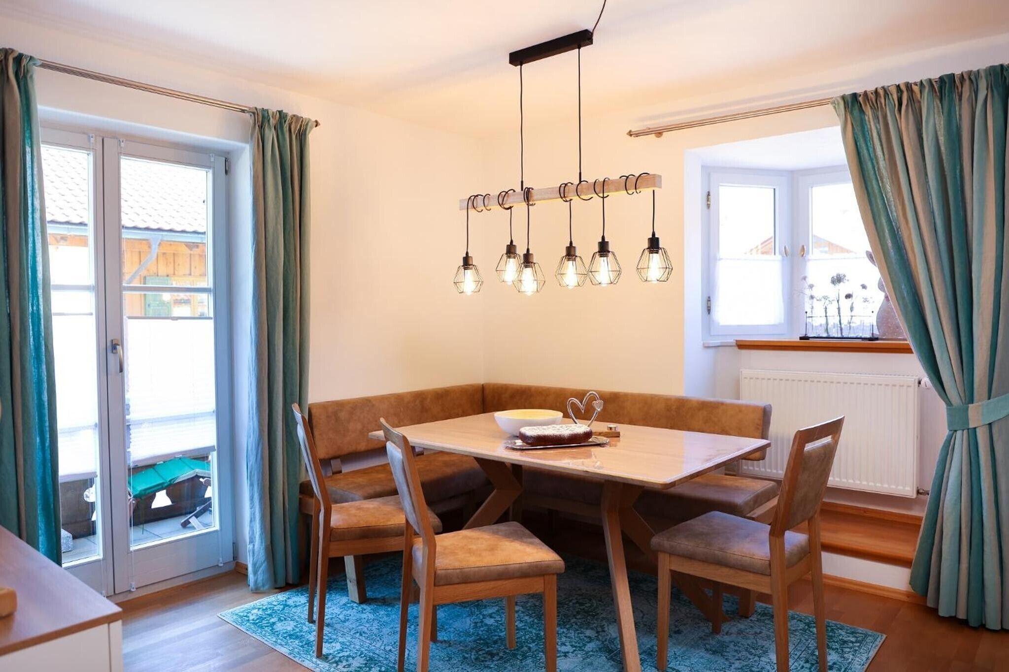 Ein Essbereich mit einem Holztisch, gepolsterten Bänken und Pendelleuchten.