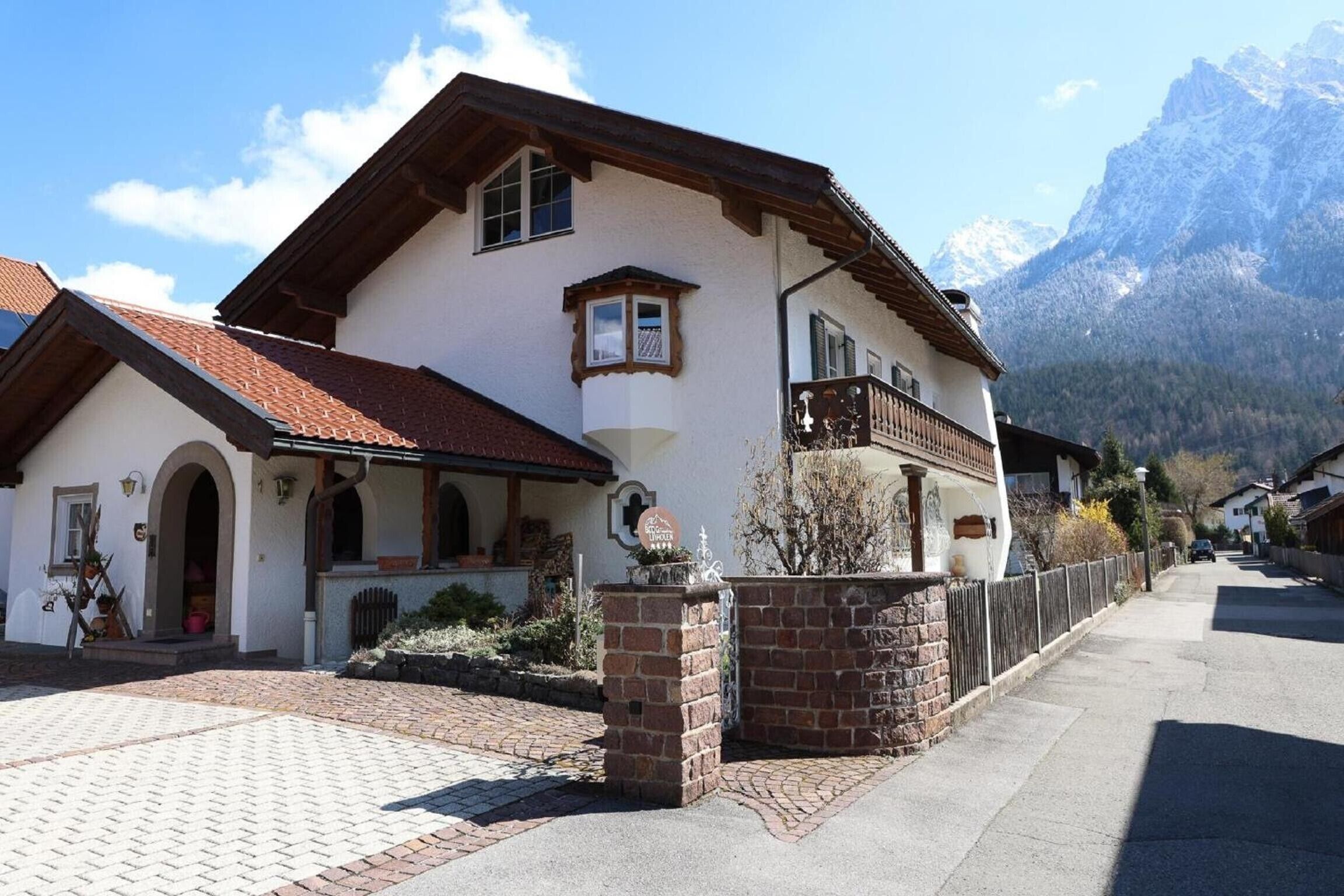 Een klassiek chalet met een stenen deuropening, een balkon en een berg op de achtergrond.