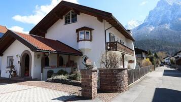 Een klassiek chalet met een stenen deuropening, een balkon en een berg op de achtergrond.
