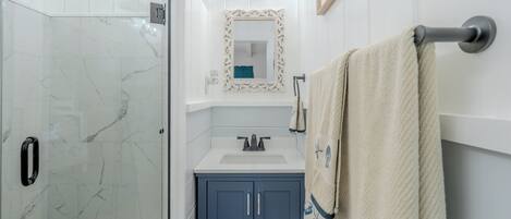 A bathroom with a shower, sink, and vanity.
