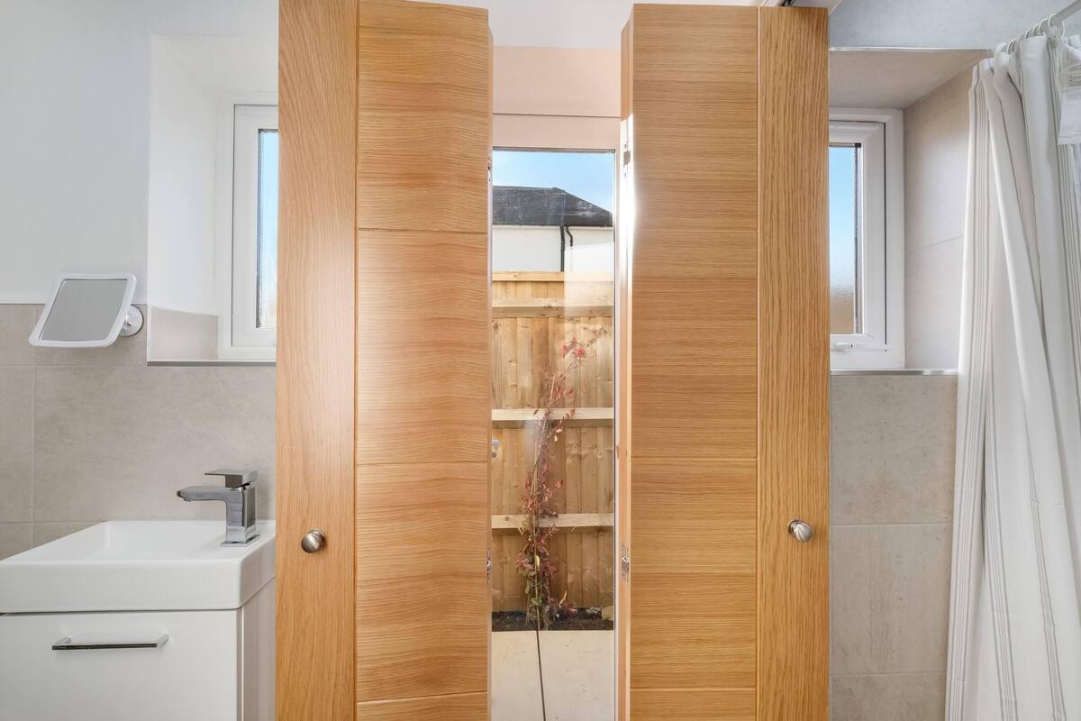 A bathroom with a wooden door, a white sink, and a window.