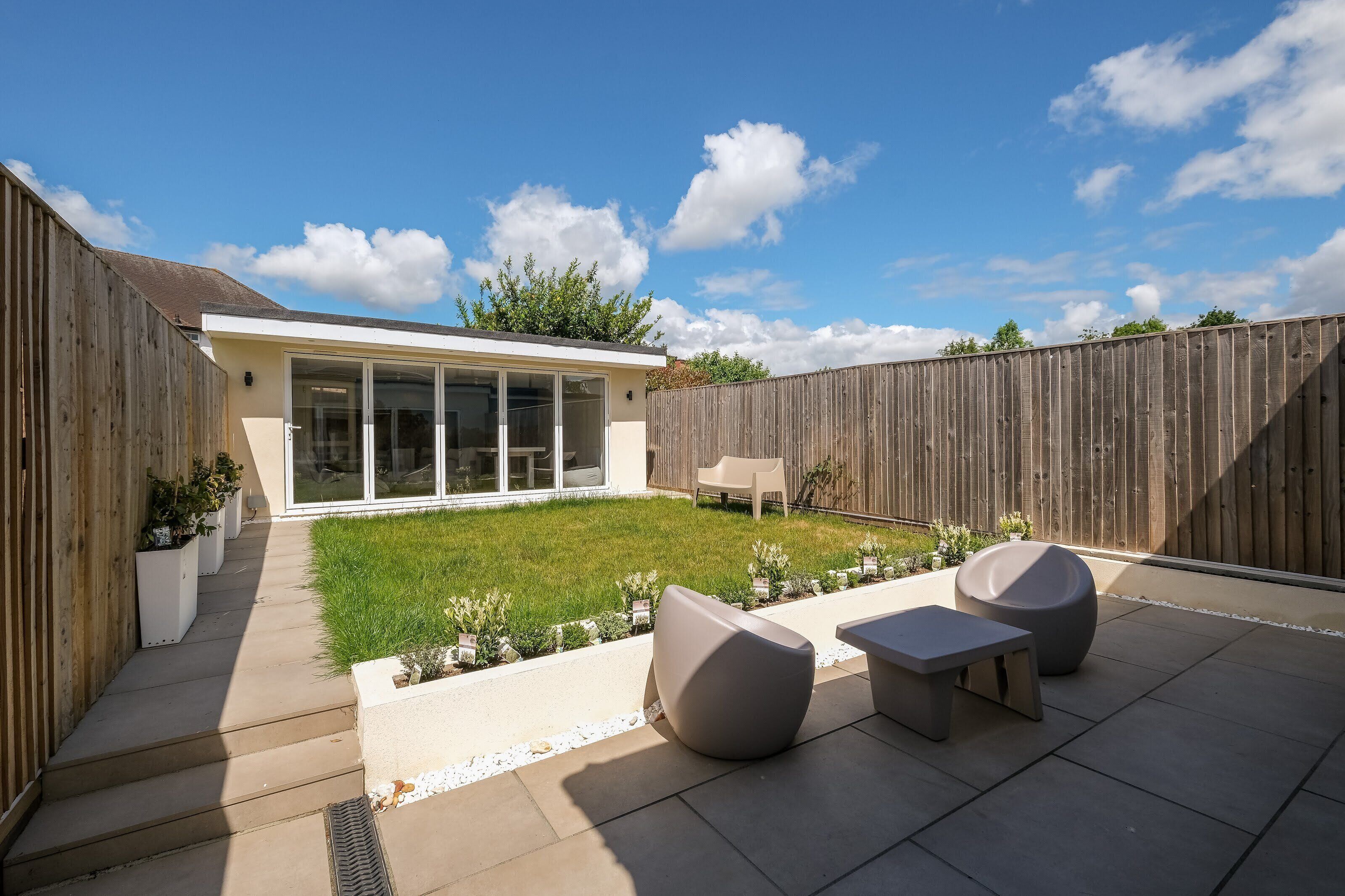 A backyard with a patio, outdoor seating, and a wooden fence.
