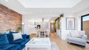 A modern living room with a blue sofa, a white coffee table, and a grey armchair. - Bright 6 bedroom 3 bath house ideal for Pinewood Studios (Iver)