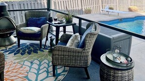 A covered outdoor patio with wicker furniture, a pool, and a view of a wooded area. - Spacious 5-bedroom house in Evans- Perfect for the Masters Golf Tournament (Evans)