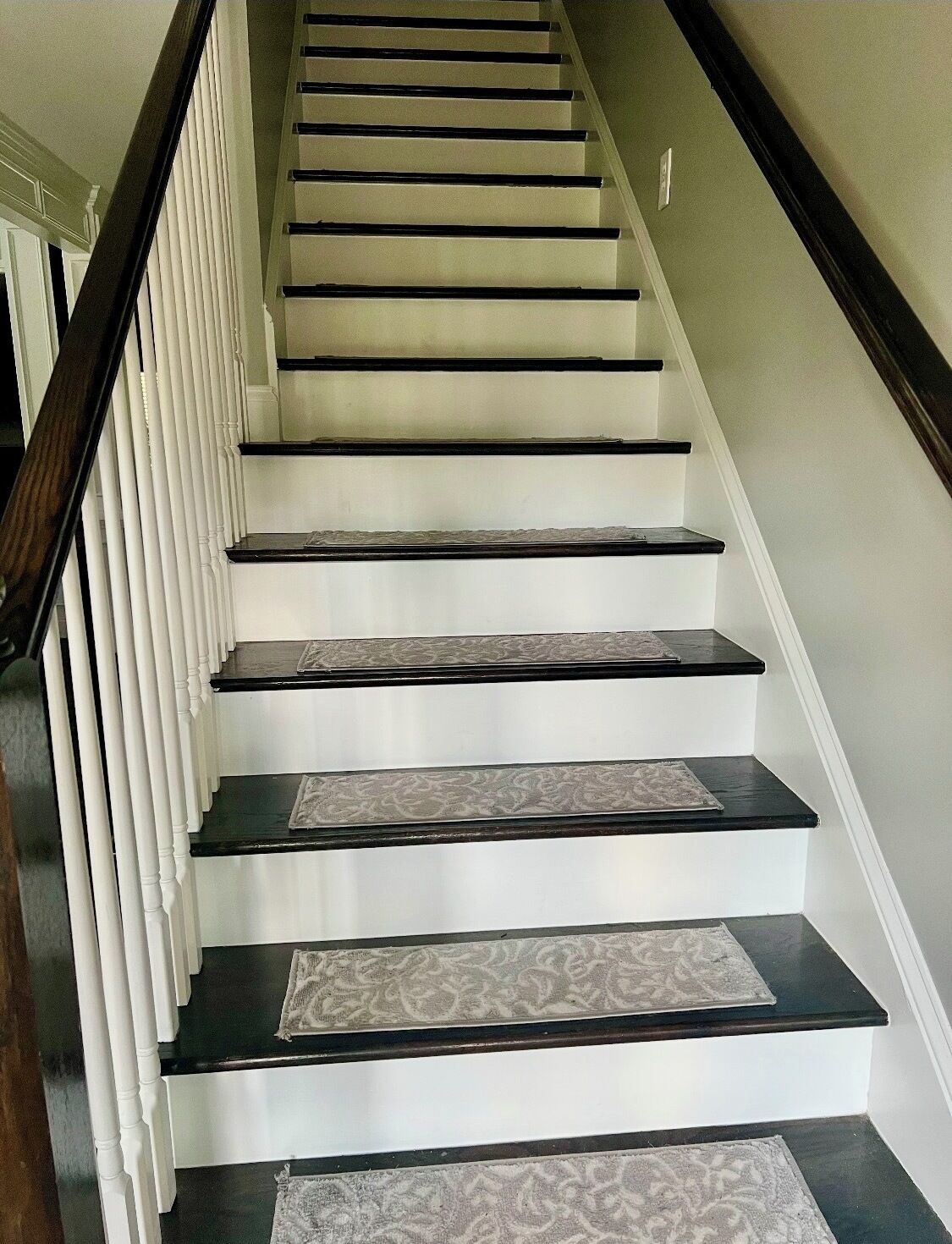 A staircase with white walls and dark wooden steps.
