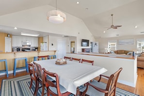 A spacious kitchen with a central island, wooden chairs, a dining table, and a ceiling fan. - Sounds like a Plan: Pool | Hot Tub | Elevator | Dogs OK (Kill Devil Hills)