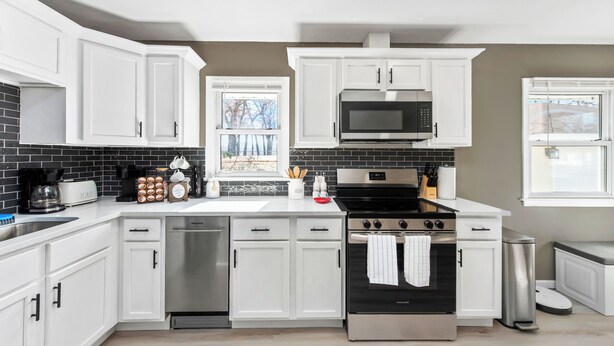 Une cuisine moderne avec des armoires blanches, une cuisinière en acier inoxydable et un four à micro-ondes.