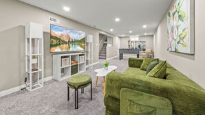 Un salon moderne avec un grand téléviseur à écran plat, un canapé vert et une petite table basse blanche.