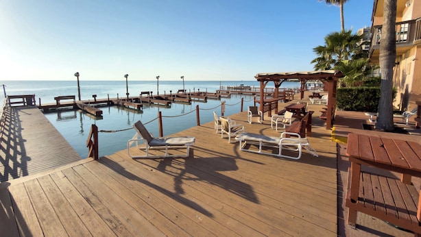A wooden deck with lounge chairs and a pool area overlooking the sea. - Direct Bayfront Sunsets - Boat Docks - Pool - Fish (South Padre Island)