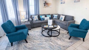 A living room with a sectional sofa, two armchairs, a coffee table, and a ceiling fan. - Direct Bayfront Sunsets - Boat Docks - Pool - Fish (South Padre Island)