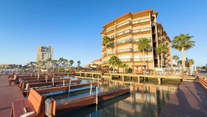 A multi-story hotel with balconies, a pool area with wooden decks, and palm trees. - Direct Bayfront Sunsets - Boat Docks - Pool - Fish (South Padre Island)