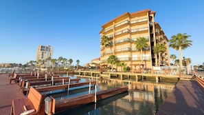 Um hotel com vários andares, varandas, área de piscina com decks de madeira e palmeiras.