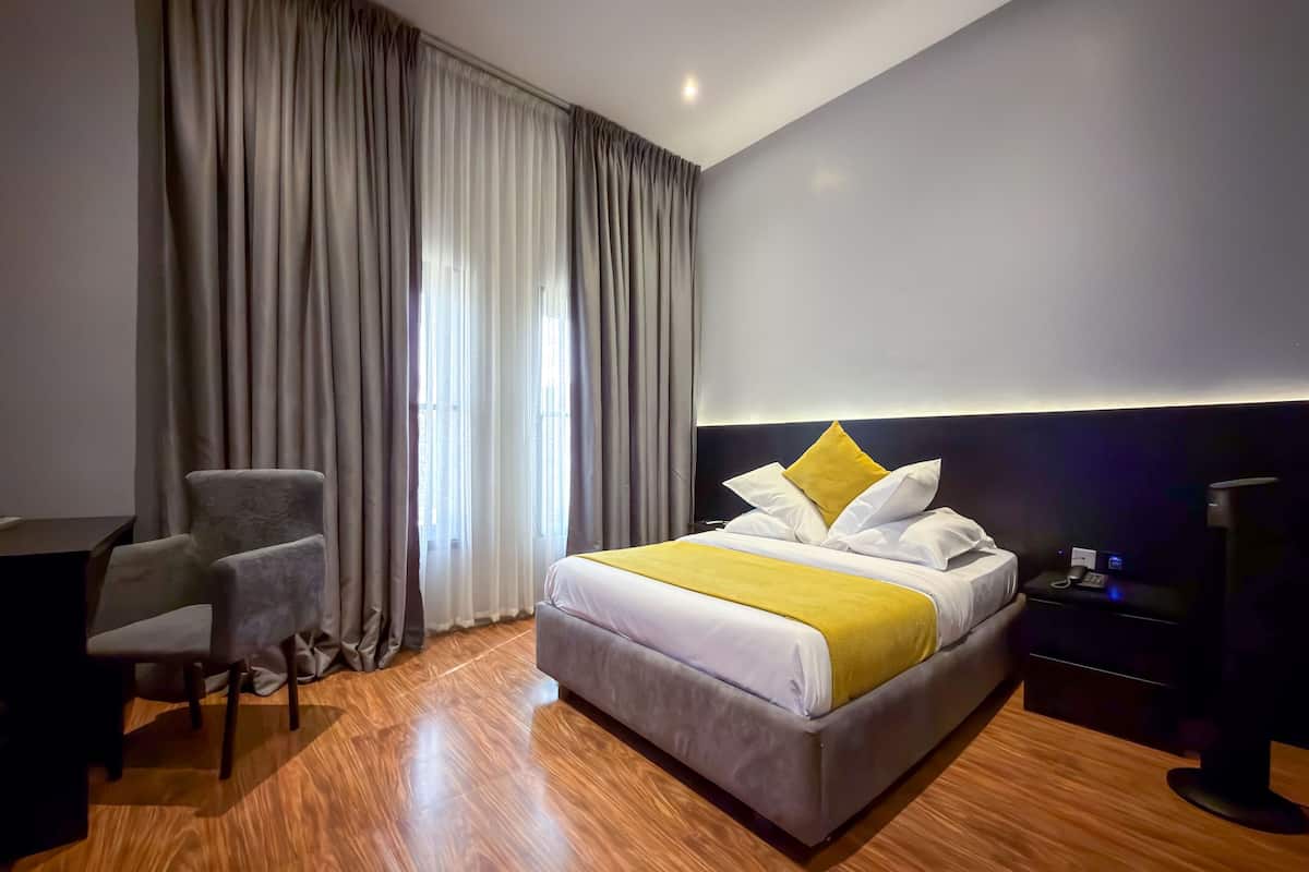 A hotel room with a bed, a desk, a chair, and a nightstand.