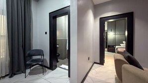 A modern hotel room with a seating area, a bathroom with a mirror, and a separate bedroom with a bed. - PEREGRINE HOTEL BY BOULEVARD (Jos)