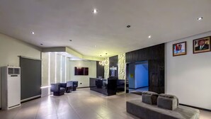 A modern lobby with a reception desk, seating area, and a large mirror. - PEREGRINE HOTEL BY BOULEVARD (Jos)