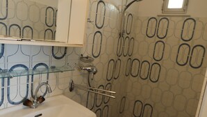 A bathroom with a white sink, a mirror, a shower, and a patterned wall.