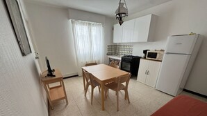 A compact kitchen with a dining table, chairs, a refrigerator, a stove, and a microwave.