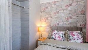 A bedroom with a bed, a nightstand, a lamp, and a wardrobe. - The Comfort Den (Aberystwyth)