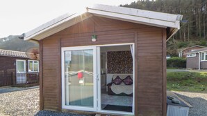 A small wooden building with a glass door and a step leading to the entrance. - The Comfort Den (Aberystwyth)