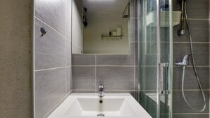 A modern bathroom with a glass-enclosed shower, a white sink, and a mirror.