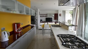 A modern kitchen with a gas stove, white cabinets, and a yellow accent wall. - A 5 minuti dal Lago di Tenno, spaziosa villa con piscina vista Lago di Garda (Trentino-Alto Adige)
