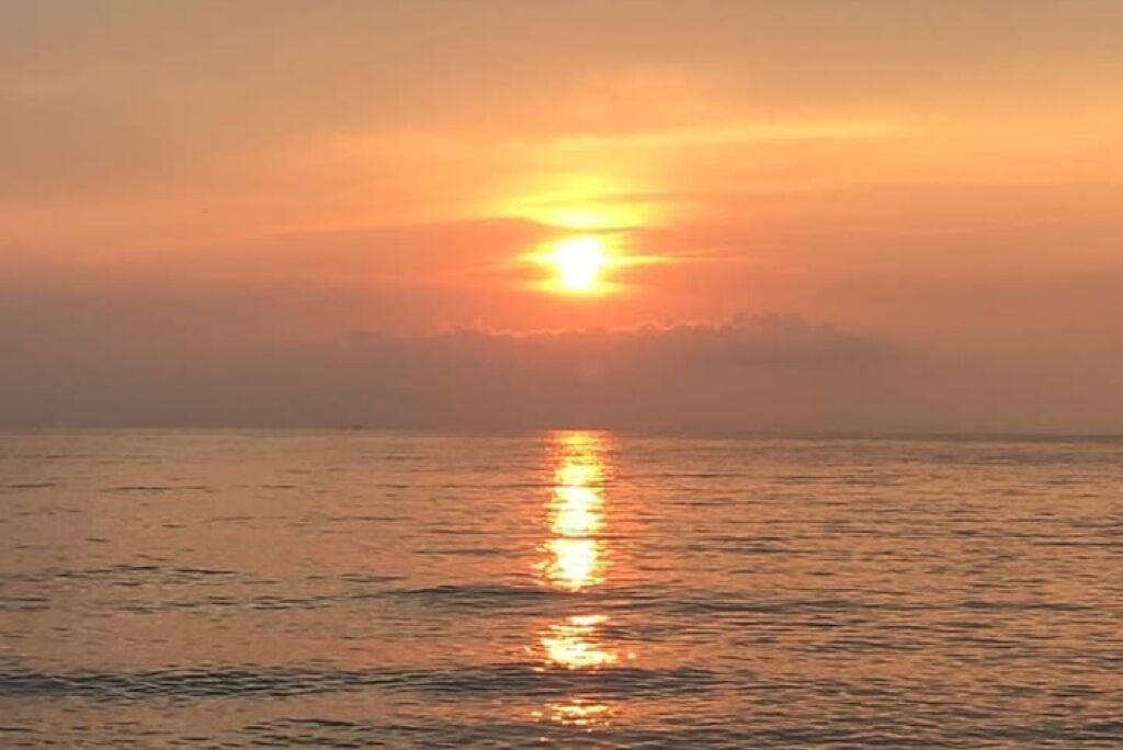 A sunset over a calm sea with a clear horizon.