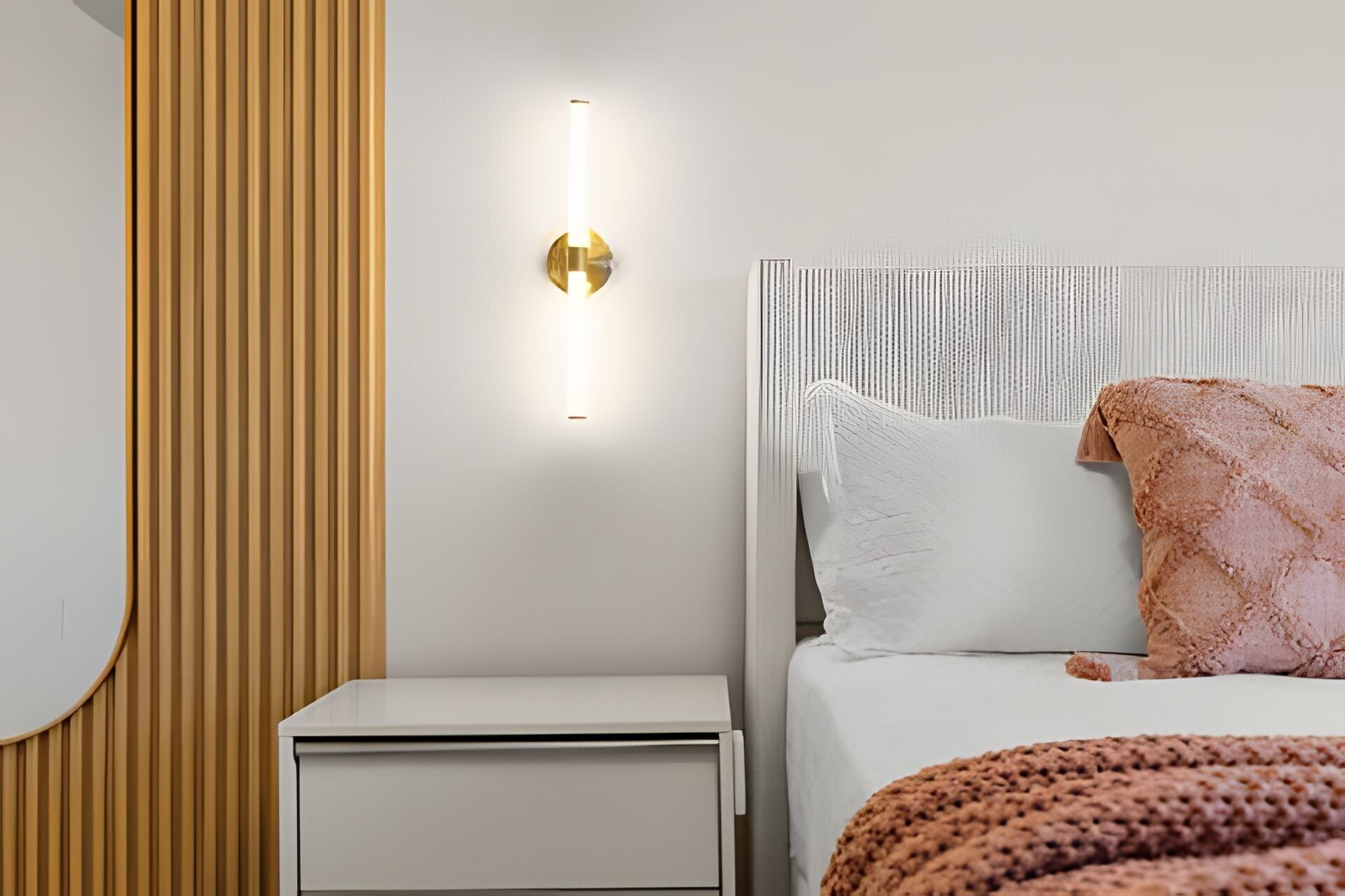 Ein Schlafzimmer mit einem Bett, einem Nachttisch und einer Wandleuchte.