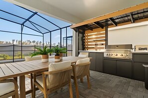 Eine Außenküche mit Holztisch und Stühlen, einem Grill und Blick auf die Stadt.