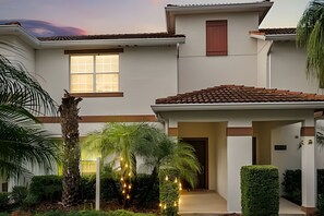 Ein zweistöckiges Haus mit Ziegeldach, Hauseingang und überdachter Veranda.