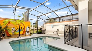 Une piscine intérieure dotée d’une paroi vitrée, une fresque murale et un espace détente avec un fauteuil.
