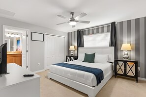 Ein Hotelzimmer mit Bett, Nachttischen, Deckenventilator und einem Fenster mit Vorhängen.