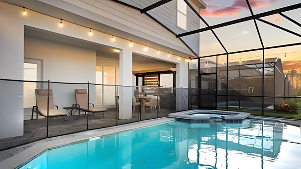 Une piscine intérieure moderne avec des parois en verre transparent, un jacuzzi et un espace détente avec des fauteuils et une table.