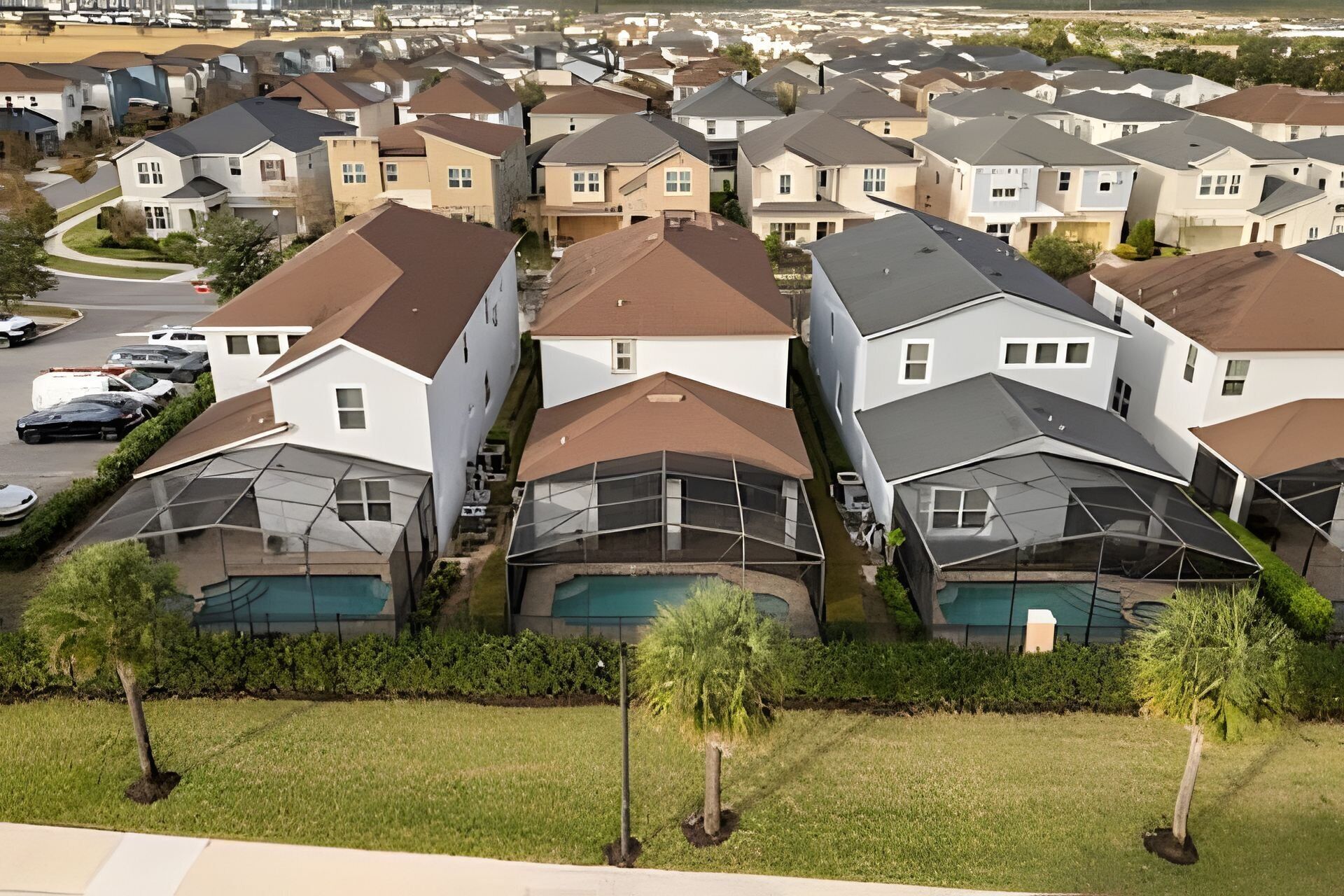 Un quartier résidentiel avec des maisons modernes, chacune dotée d’un espace extérieur abrité, vraisemblablement une terrasse ou un patio, et d’une piscine visible.