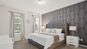 Une chambre moderne avec un grand lit, des tables de chevet, une fenêtre avec des rideaux et un mur décoré de motifs.