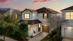 Une maison à deux étages avec un porche à l’avant, un garage et un jardin bien entretenu.
