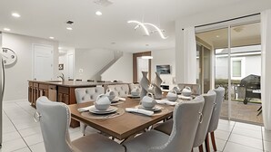 Un espace repas moderne avec une table en bois, des chaises à revêtement gris et des objets de poterie décoratifs.