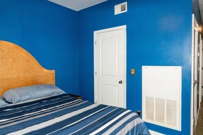 Ein Schlafzimmer mit einem Bett, einer weißen Tür und einem Fenster mit Jalousien.