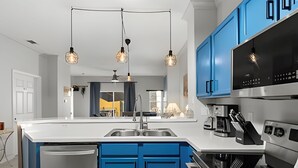 Eine moderne Küche mit blauen Schränken, einem Edelstahlkühlschrank, einer Spüle und einem eingebauten Backofen.