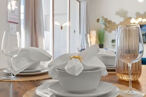 Ein gedeckter Tisch mit weißem Geschirr, einer Schüssel und einem Wasserglas.