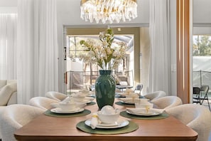 A dining area with a table set for four, a green vase with flowers, and a chandelier. - 4 Bd / 3 Ba / Sleeps 11/ Storey Lake Resort (Kissimmee)