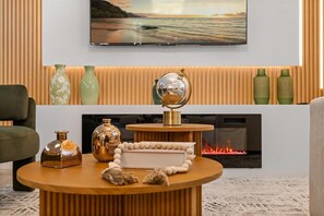 A modern living room with a fireplace, a television mounted on the wall, and decorative vases on the mantel. - 4 Bd / 3 Ba / Sleeps 11/ Storey Lake Resort (Kissimmee)