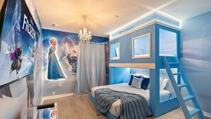 Un dormitorio con una cama litera, un mural de personajes de Frozen, una araña y una escalera para acceder a la cama litera.