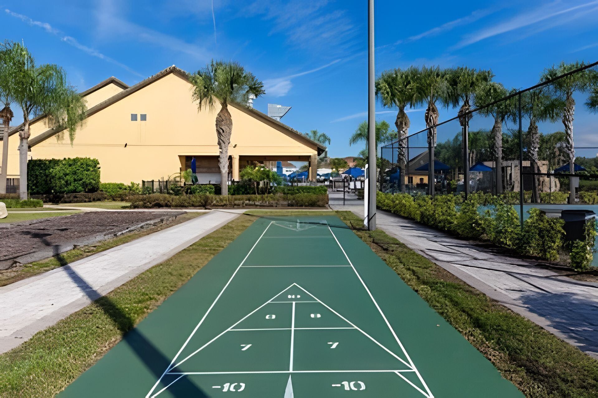 A shuffleboard court adjacent to a yellow building with a covered patio area.