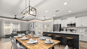 Una cucina moderna con mobili bianchi, un frigorifero in acciaio inossidabile e un forno a microonde.