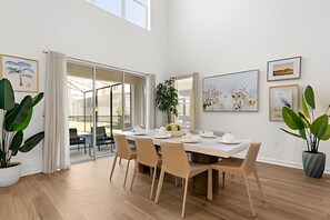 A spacious dining area with a large table, multiple chairs, and a sliding glass door leading to an outdoor patio. - 5 Bd / 5 Ba / Sleeps 14 / Reunion Village (Kissimmee)
