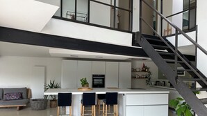 Eine moderne Küche mit einer zentralen Kochinsel, einer Treppe und einem Hund im Vordergrund.