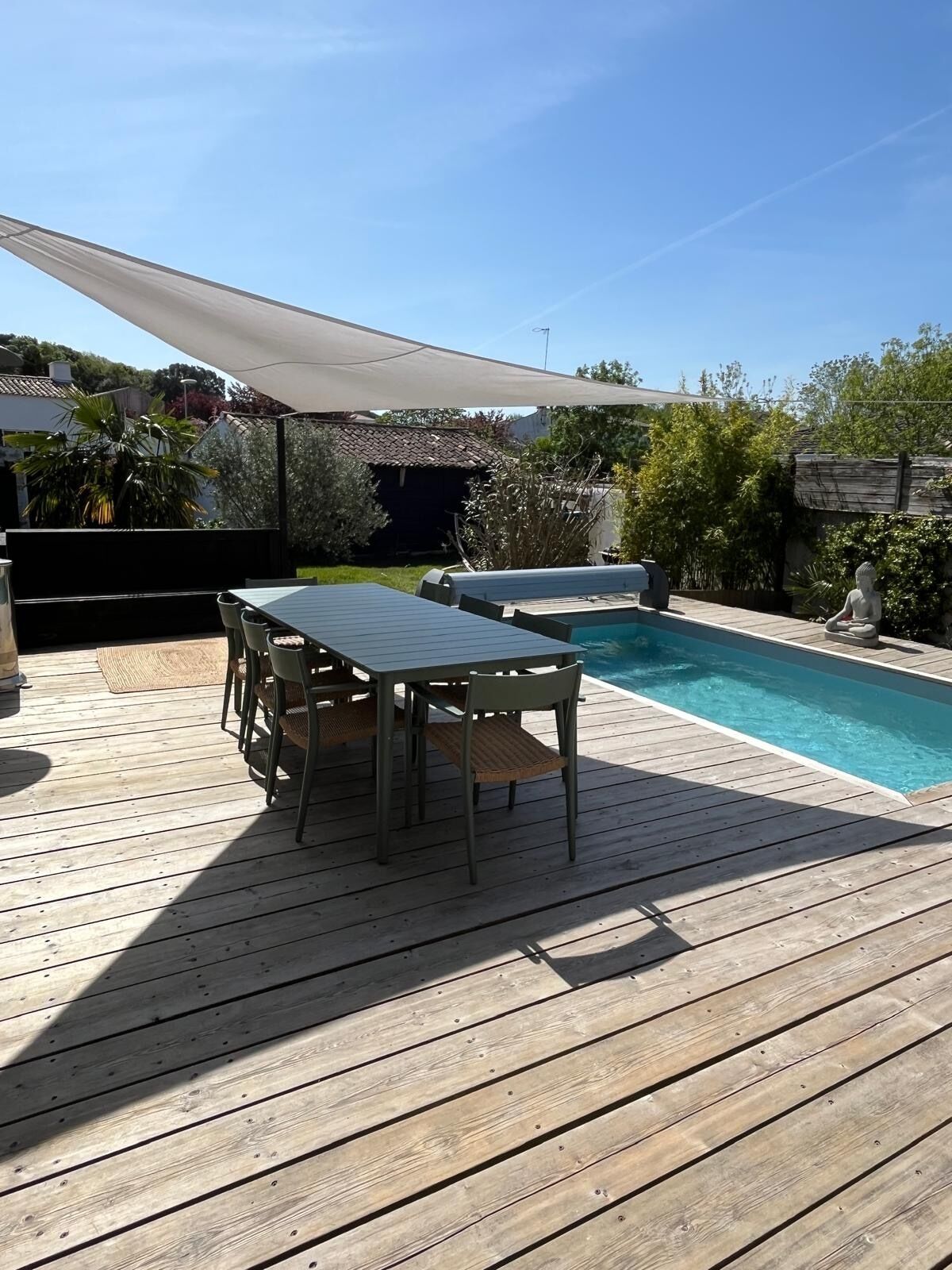 A wooden deck with a pool, a table, and chairs.